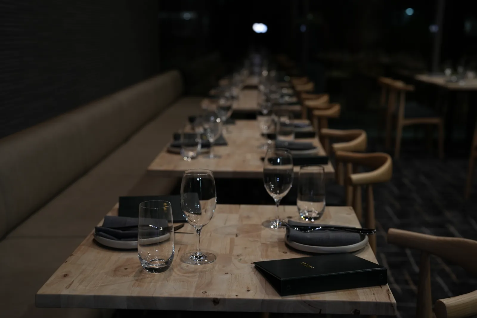 The candlelit Rakkas dining room - the long communal table set with wine glasses against dark walls