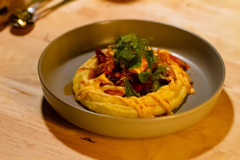 Prawns on saffron potato purée with herbs in a grey bowl at Rakkas